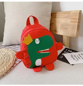 Gros plan sur le sac à dos dinosaure rouge pour enfants avec détails 3D verts et couronne jaune.
