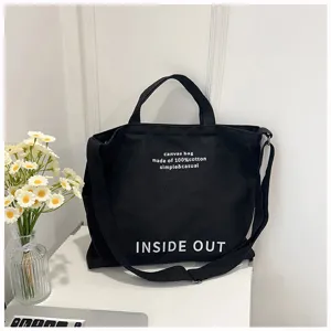 Black canvas tote bag, large capacity crossbody shoulder bag with printed letters, detail view.