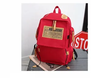 Close-up detail of red Oxford fabric backpack with tan leather accents and pocket design.