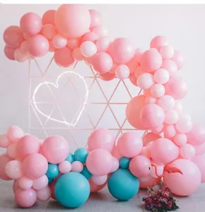 Party balloon arch decoration set with pink and blue balloons and neon heart light backdrop.