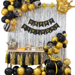 Black gold birthday party balloon set with silver fringe curtain backdrop and banner decorations.