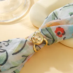 Primo piano dettaglio di un anello per sciarpa in metallo dorato con strass stella chiaro su tessuto.