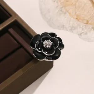Squisito copribototone da camicia a camelia nera con perla centrale, elegante accessorio vintage.