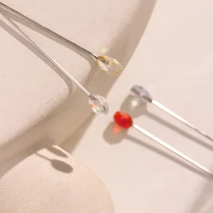 Detailed shot of elegant hijab pins with sparkling crystal beads and fine metal shafts.