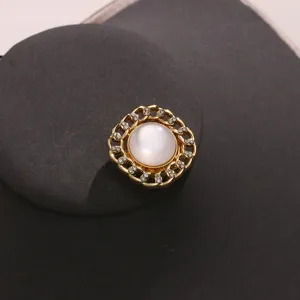 Elegante copribottone a catena dorata con perla centrale e strass per abiti eleganti.