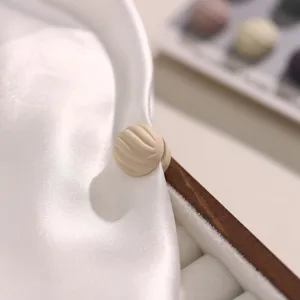 Detailopname van beige getextureerde magnetische hoofddoekspeld op witte zijden stof.