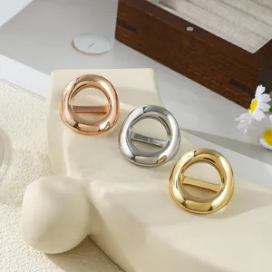 Dettaglio di tre anelli metallici per sciarpa in oro rosa, argento e oro su un supporto.