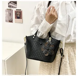 Black textured shoulder crossbody handbag with elegant flower charm and gold hardware for women.