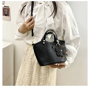 Detailed view of women's black woven crossbody bag, highlighting exquisite leather and hardware.