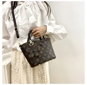Detail view of a stylish brown monogram bucket shoulder bag with top handle and strap.