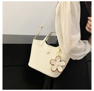 Elegant white bucket bag with floral charm, stylish shoulder crossbody bag for women.