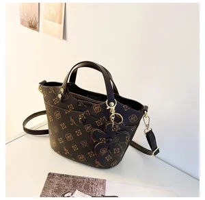 Detail view of stylish women bucket bag with retro monogram pattern and cute floral charm.