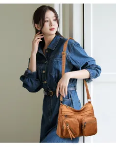 Vista dettagliata della borsa in pelle marrone con tasche multiple indossata al chiuso.
