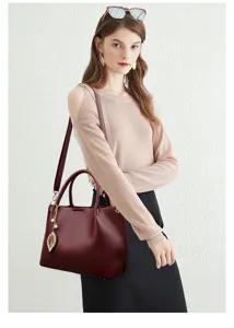 Elegant burgundy leather women handbag with stylish leaf charm, spacious tote shoulder bag for daily use.