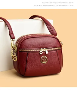Detailansicht der mehrlagigen Umhängetasche für Damen aus Leder mit goldenen Reißverschlüssen.