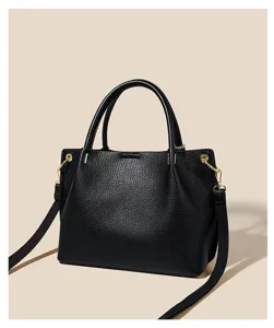 Detailed view of the black pebbled leather handbag featuring gold hardware and handles.