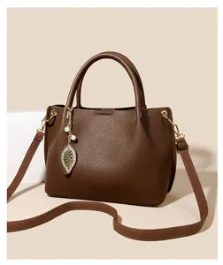 Detailed view of brown women soft leather tote bag with leaf pendant shoulder crossbody style.