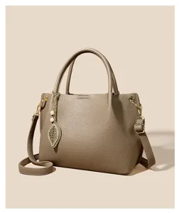 Detail view of the elegant taupe leather tote bag featuring a delicate leaf and pearl pendant.