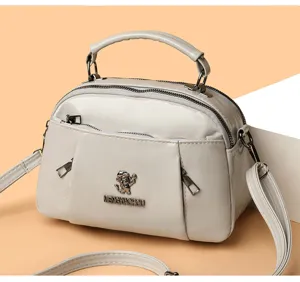 Chic women's PU leather crossbody bag with top handle, dual zippers and stylish metal front logo.