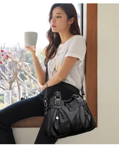 Detail view of black leather shoulder bag featuring large capacity and multiple zipper pockets.