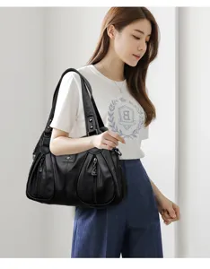 Detail view of the black leather shoulder handbag featuring dual straps and pockets.