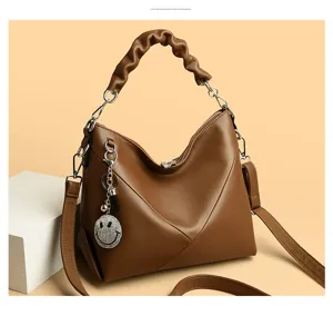 Brown leather shoulder bag with pleated top handle and rhinestone smiley charm detail.