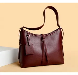 Detailed view of the dark red leather shoulder bag, featuring hanging tag and strap details.