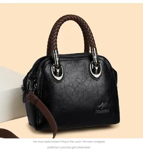 Detailed view of black leather dome handbag featuring brown braided top handles and metal hardware.