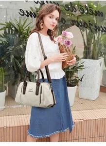 Detailed view of the stylish commuter handbag with brown leather handles and adjustable strap.