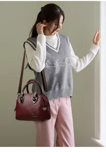 Detailed view of the dark red leather handbag showcasing woven handle and metal hardware accent.