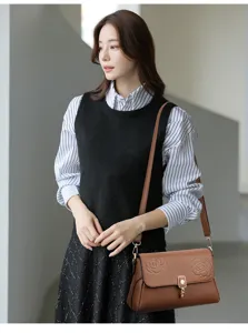 Detailaufnahme einer braunen Ledertasche mit elegantem Prägerosenmuster und Metallverschluss.
