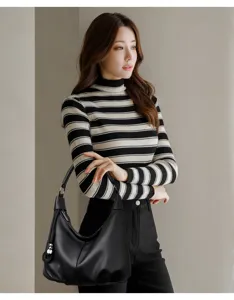 Detail view of a stylish black leather hobo shoulder bag worn by a model in casual knitwear.