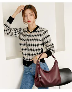 Details of the stylish burgundy hobo shoulder bag with tassel charm and soft leather material.