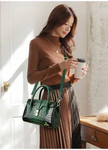 Detailed view of the dark green crocodile pattern patent leather shoulder bag with gold.