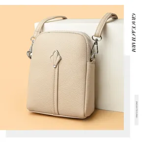 Close-up detail of beige crossbody phone bag with metal clasp and leather texture.