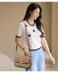 Vue détaillée d'un sac à bandoulière à carreaux marron associé à un haut en tricot fleuri chic.