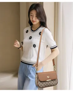Vue détaillée d'un sac à bandoulière élégant pour femmes avec monogramme et haut en tricot chic.