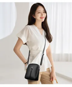 Detailed shot of the black leather mini cross-body bag, showing texture and hardware.
