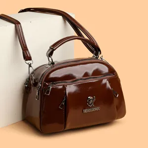 Women brown patent leather dome satchel crossbody bag with top handle and double zippers.
