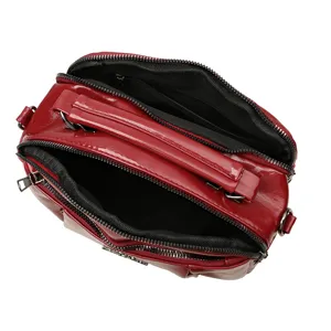 Red patent leather crossbody bag with top handle and double zipper compartments for women.