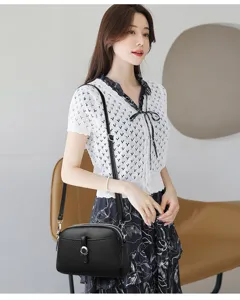 Close-up view of a stylish black leather crossbody shoulder bag worn by a model.