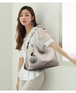 Detailed view of grey hobo shoulder bag, rhinestone smiley pendant, delicate leather texture.