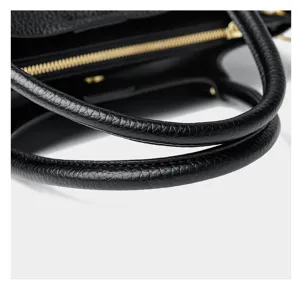 Close-up detail view of black leather handbag handle and gold zipper, premium texture.