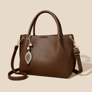 Brown leather tote bag for women, stylish large capacity shoulder crossbody bag with leaf pendant.