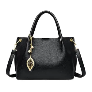 Women's black leather handbag large capacity top handle shoulder crossbody bag with leaf pendant.