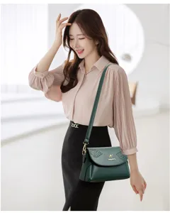 Detail view of dark green leather shoulder bag featuring leaf embossing and metallic kangaroo logo.
