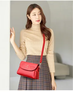 Stylish red leather women's shoulder bag with chic leaf embossing and elegant metal logo.