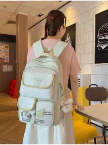 Multi-compartment canvas backpack lifestyle detail showing spacious pockets and cute cartoon charms.