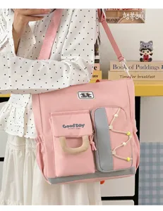 Bolso de hombro rosa de lona con múltiples bolsillos y detalle de compartimento delantero.