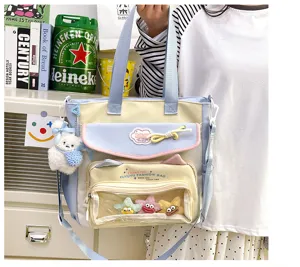 Detail view of the cute canvas shoulder bag with transparent window, multi-pocket and plush charms.